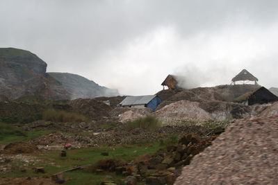 Houses by mountain against sky