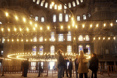 Rear view of people walking in illuminated building at night