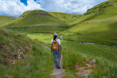 Rear view of woman walking on trail against sky