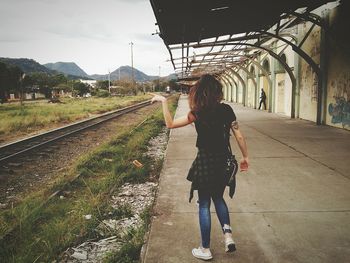 Rear view of woman walking on railroad track