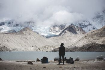 Rear view of person standing by river against mountain