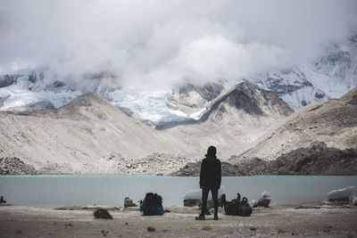 Rear view of person standing by river against mountain