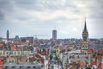 Aerial view of buildings in city against cloudy sky