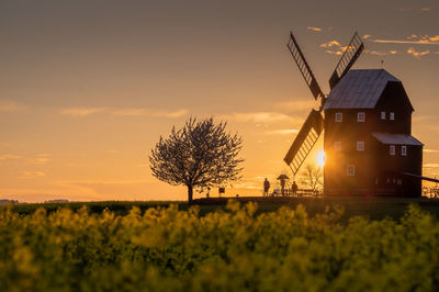 Traditional windmill on field against sky during sunset