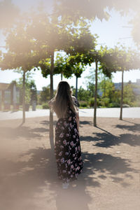 Rear view of woman standing by tree