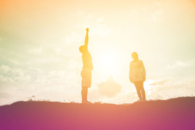 Rear view of silhouette people standing on field against sky