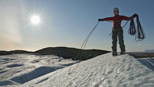 Woman taking up climbing rope on glacier in iceland