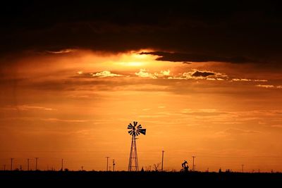 Distant old windmill against dramatic sky at sunset