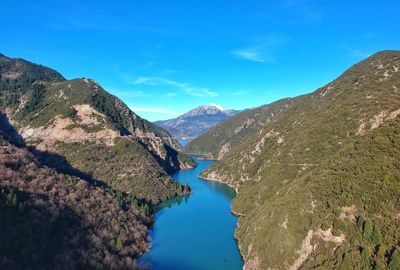 Scenic view of lake and mountains against blue sky