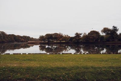 Scenic view of lake by field against clear sky