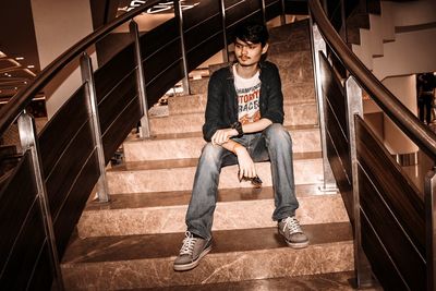 Portrait of young man sitting on staircase