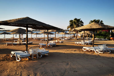 Deck chairs on beach against clear sky