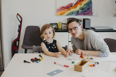 Portrait of friends sitting on table at home