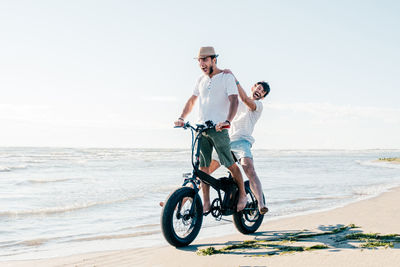 Full length of young woman riding bicycle on beach