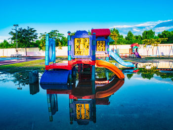 View of swimming pool by lake against blue sky