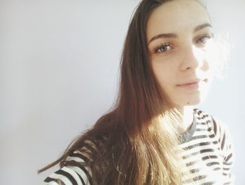 Close-up portrait of young woman standing by wall