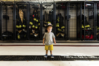 Full length of boy wearing firefighter's helmet while standing at fire station