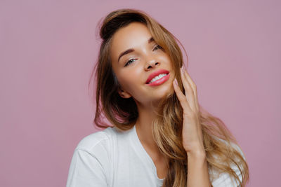 Portrait of young woman against pink background