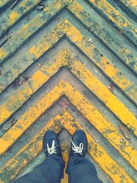 Low section of man standing on patterned footpath