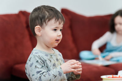 Playfull toddler is eating tomatoes while watching tv