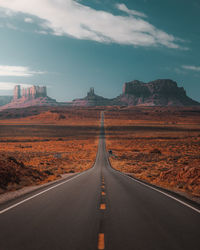 Road leading towards mountain against sky