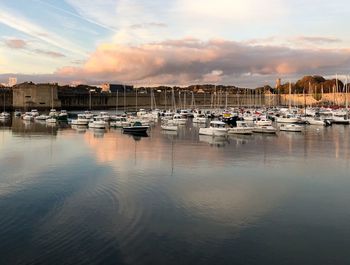 Boats moored in harbor at sunset