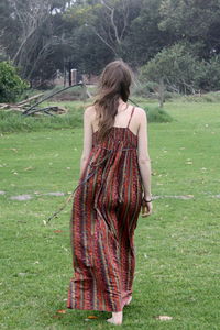 Full length rear view of woman walking on grassy field