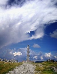 Lighthouse on field by building against sky