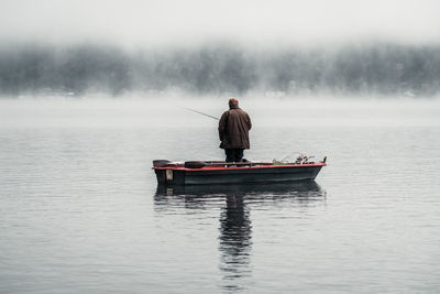 Rear view of man on boat in lake