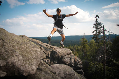 Swarthier's type of man standing on top of a rock looking down in zdarske vrchy in czech republic