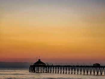 Silhouette pier over sea against sky during sunset