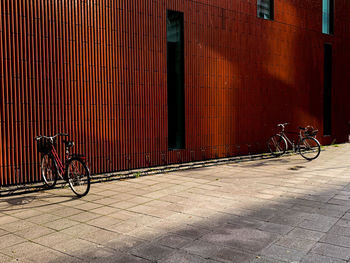 Bicycle parked on footpath against wall