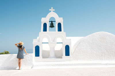 Greece, santorini, oia, back view of woman standing next to bell tower looking to the sea