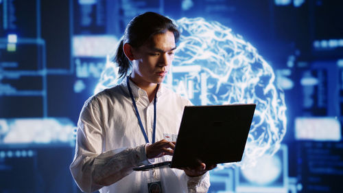 Side view of young woman using digital tablet at night