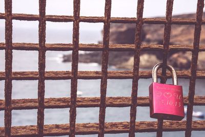 Close-up of padlocks on metal fence against sky