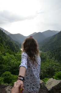 Rear view of woman looking at mountains against sky