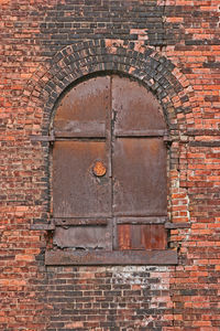 Low angle view of closed window on brick wall