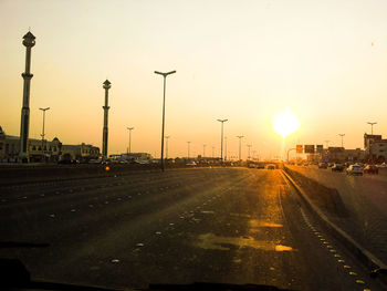 Cars on road against sky during sunset