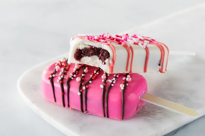 Valentine's day cakesicles on a marble slab with a bite out of the one on top.