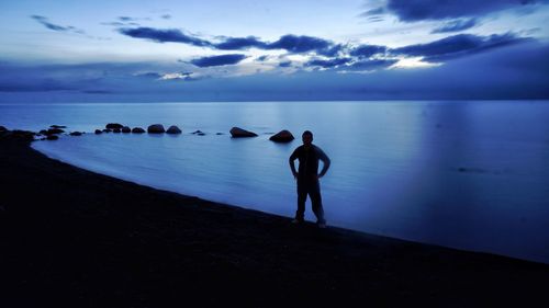 Men standing on beach against sky