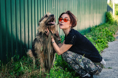 Portrait of young woman with dog on field