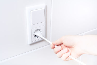 Close-up of hand plugging electric cord