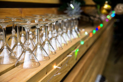 Clean martini glasses are upside down on the wooden shelf of the bar