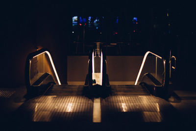 Illuminated lighting equipment on table against wall at night