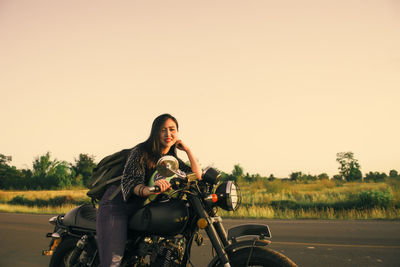 Woman riding bicycle on road against clear sky