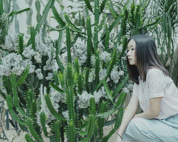 Close-up of woman crouching near cactus plants
