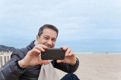 Portrait of man using smart phone on beach