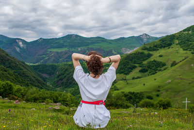 Rear view of man standing on mountain against sky