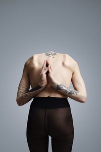 Midsection of shirtless woman with tattoo against white background