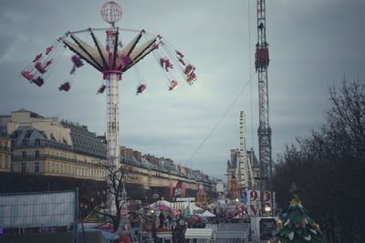 People in amusement park against sky